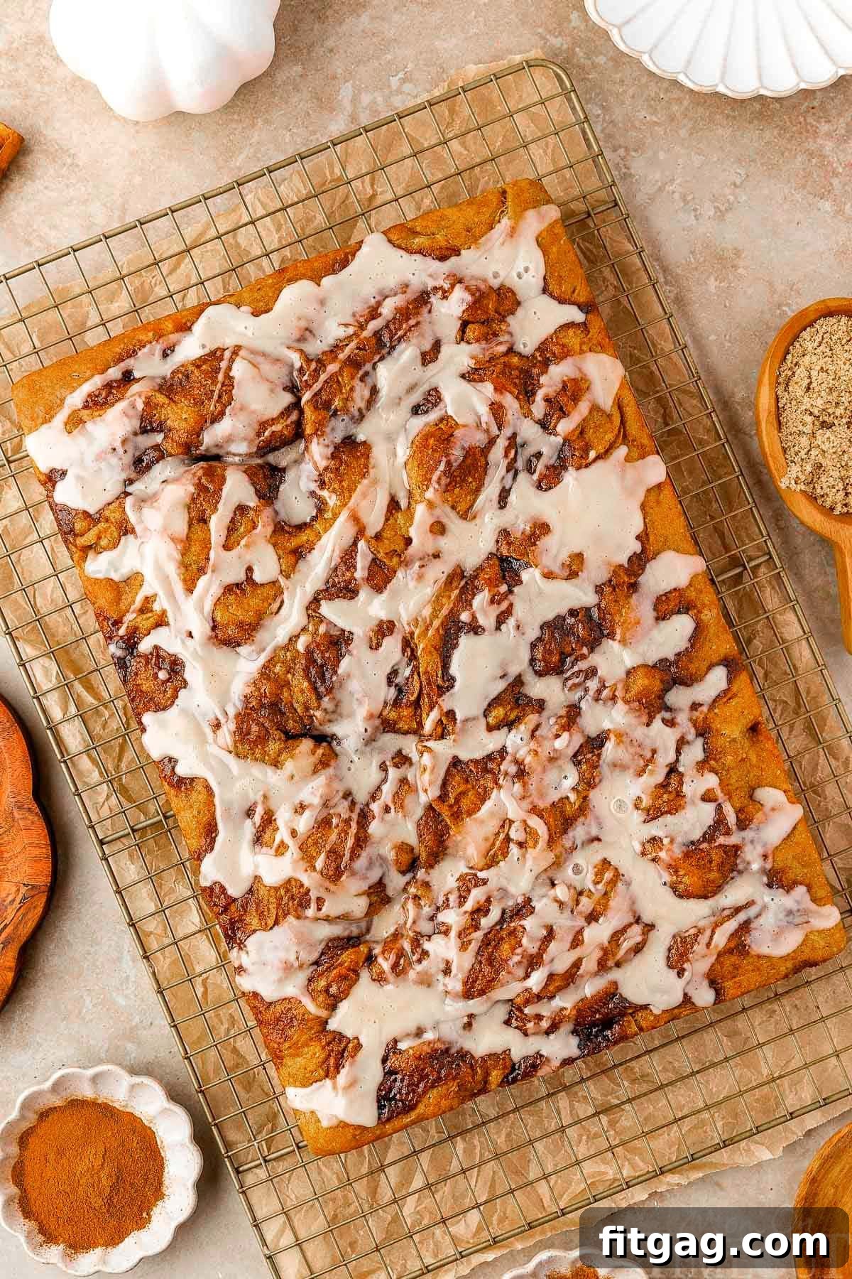 Overhead shot of pumpkin cinnamon roll focaccia recipe on cooling rack drizzled with maple glaze.