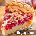 Slice of cranberry custard pie sitting on wood cutting board.