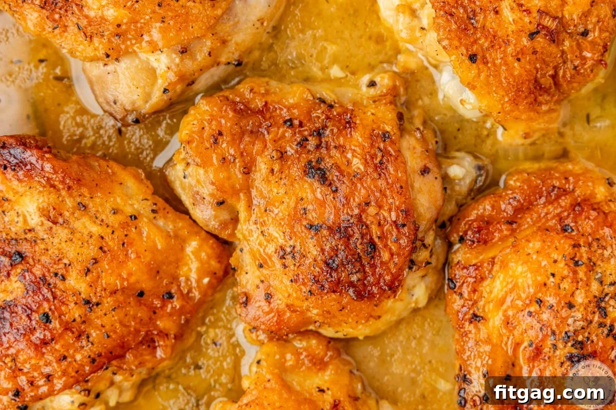Overhead shot of braised chicken thigh recipe in pan with braising liquids.