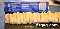 Unrolling crescent roll dough to prepare for slicing.