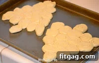 Arranging crescent roll slices into a Christmas tree shape on a baking sheet.
