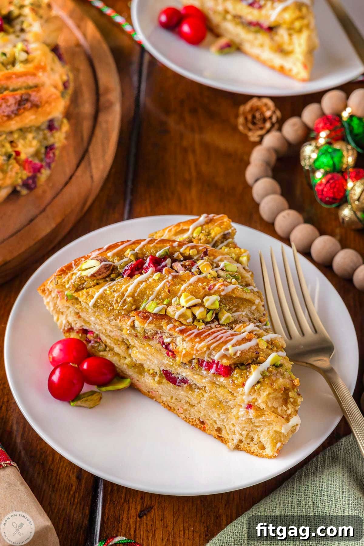 Piece of holiday babka bread on white round plate made with cranberries and pistachios.
