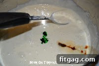 Melted marshmallows and butter in a pot, with vanilla and food coloring being added.