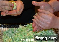 Hands mixing popcorn and marshmallow mixture in a bowl.