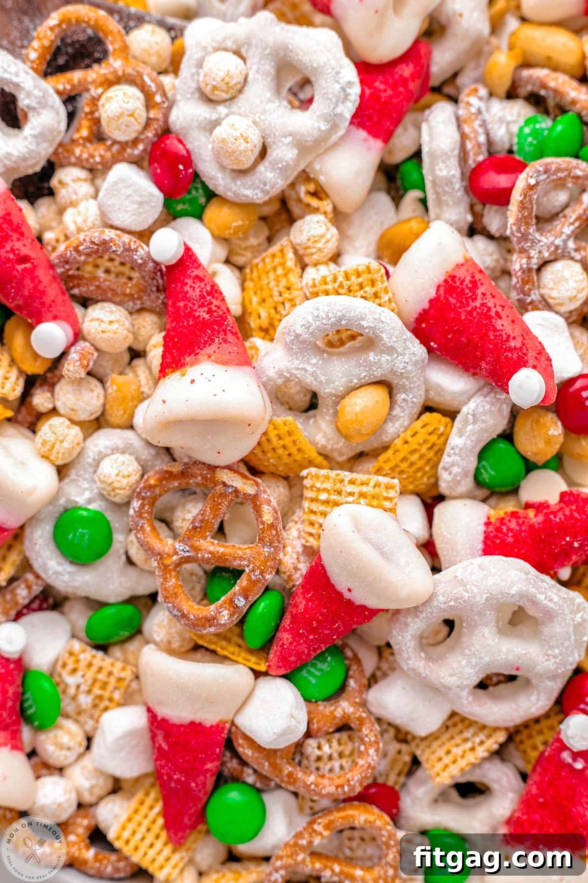 A close-up view of Santa's Christmas Snack Mix, featuring frosted cereal, mini pretzels, festive candies, and charming little Santa hat candies.