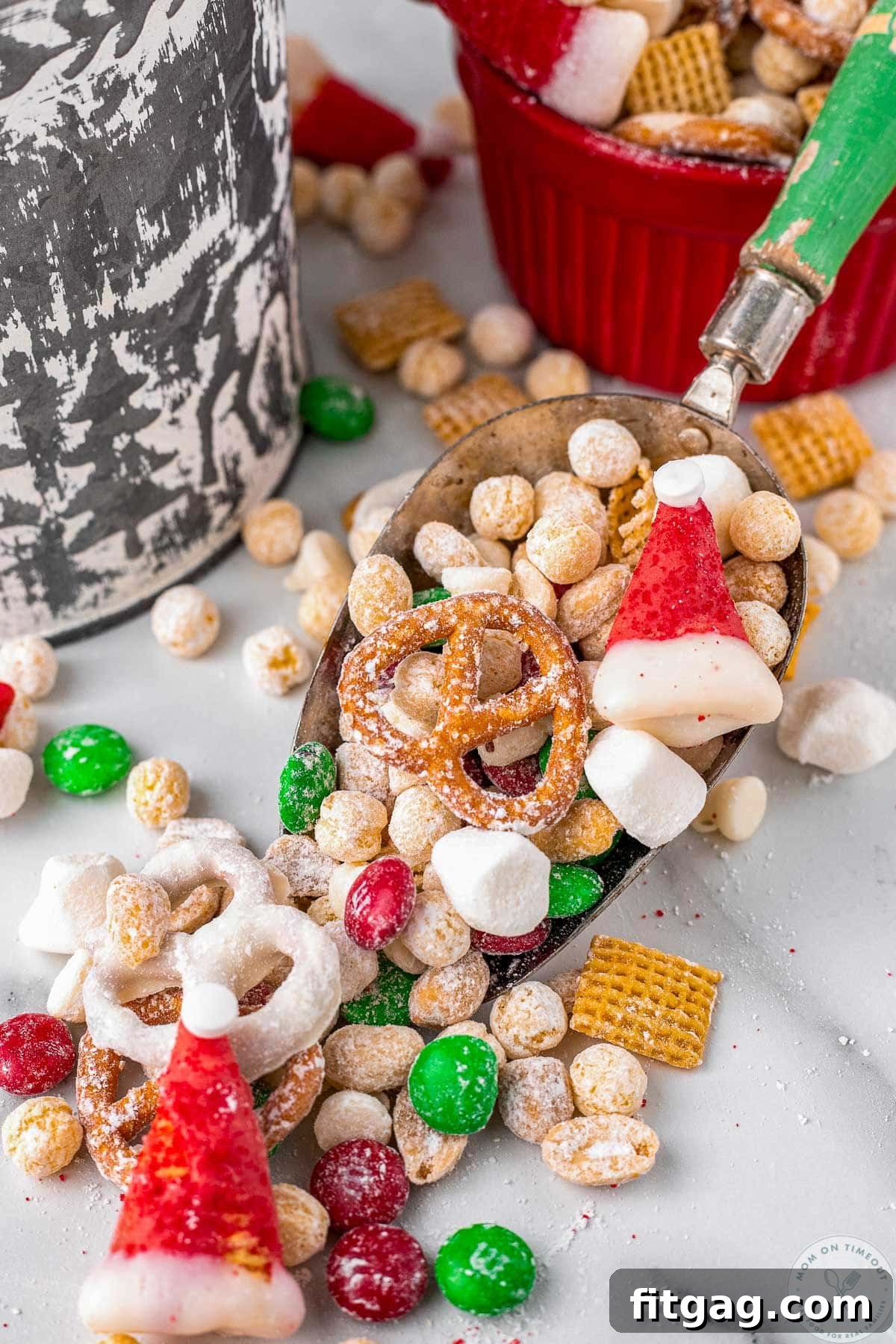 A vintage-style scoop with a green handle holding a generous serving of Santa's Christmas Snack Mix, perfect for holiday gatherings.