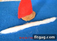 Attaching a cotton pom-pom to the tip of the Santa hat
