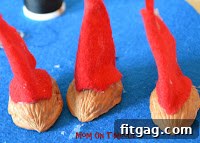 Gluing the Santa hat onto the walnut shell, securing the hanger
