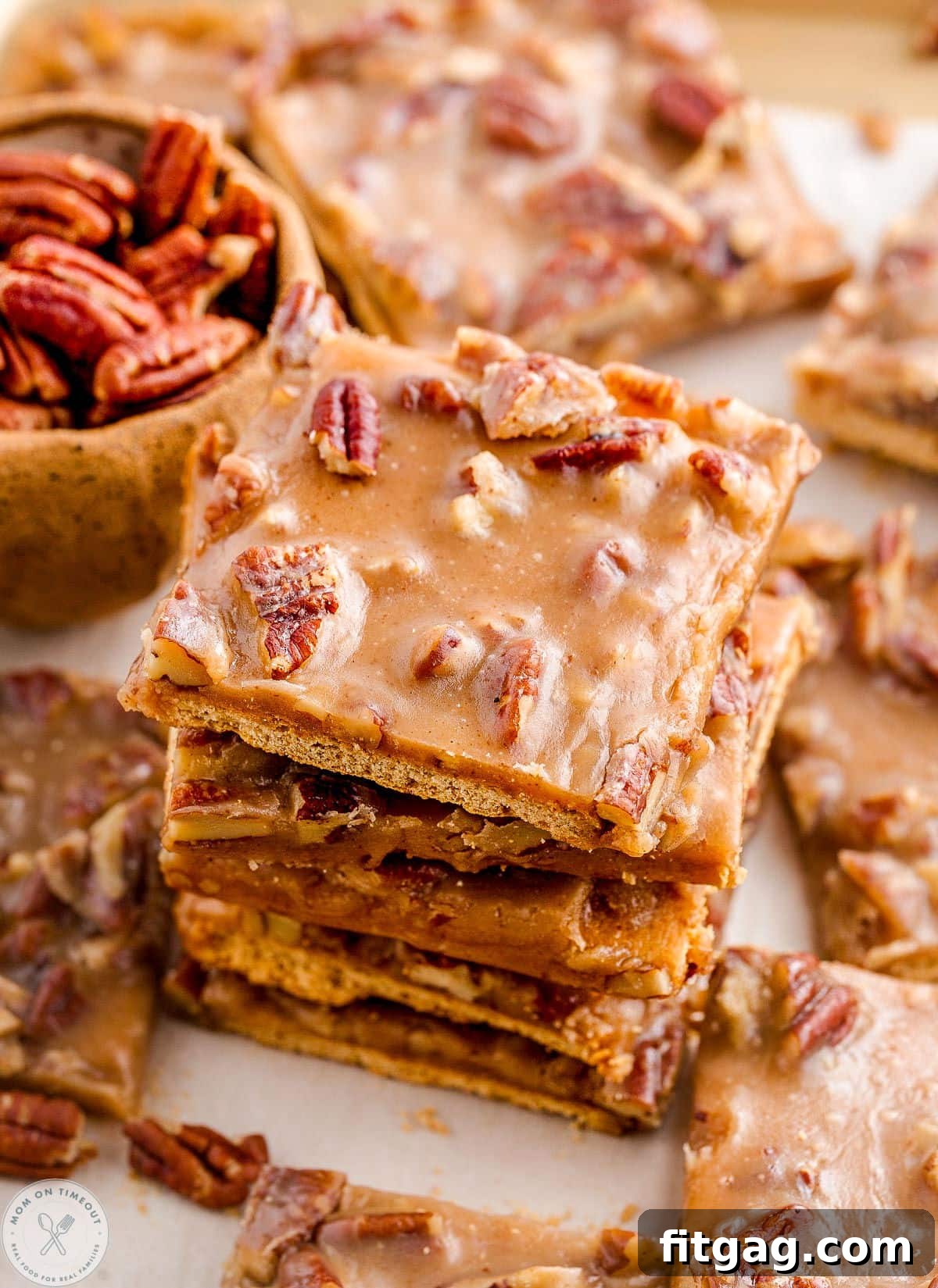 Toasted Pecan Brittle 2 Angled overhead shot of pecan pie bark next to a bowl of pecans, highlighting the texture and golden caramel.