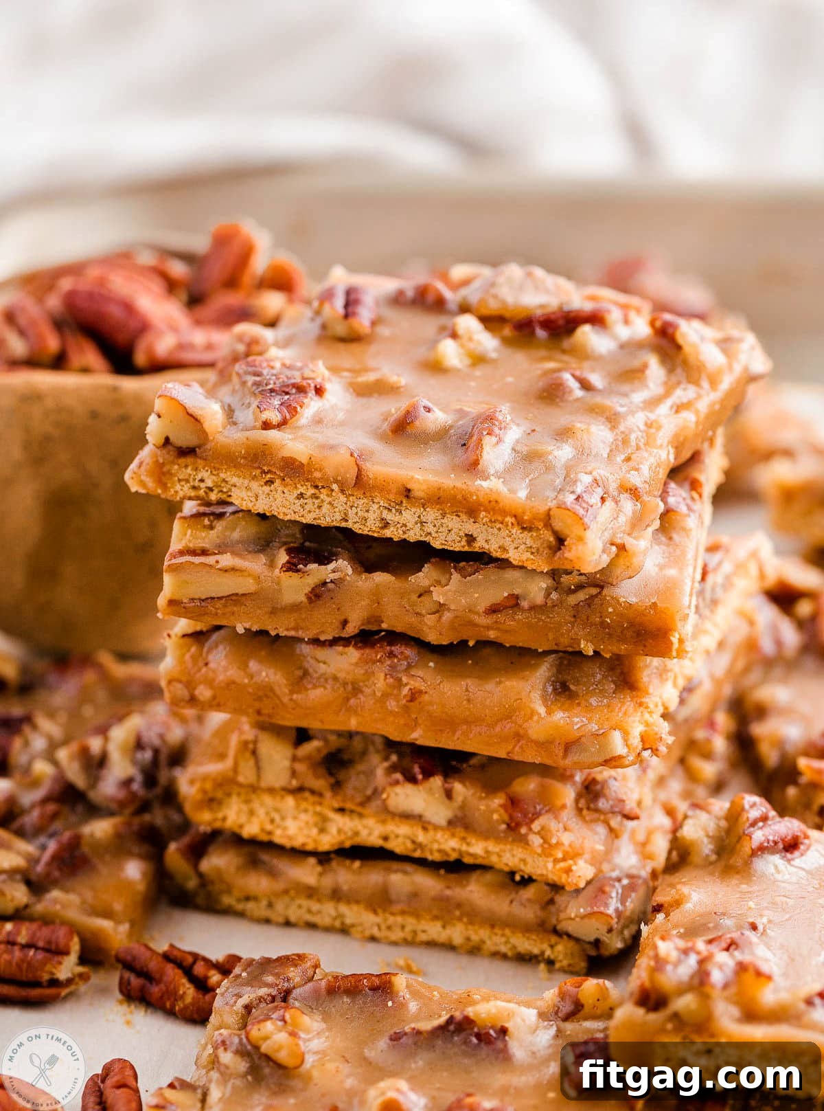 Toasted Pecan Brittle 9 Tall stack of pecan pie bark with graham crackers, surrounded by more pieces, showcasing its delightful appearance.