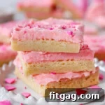Three sugar cookie bars decorated for valentine's day stacked on white plate.