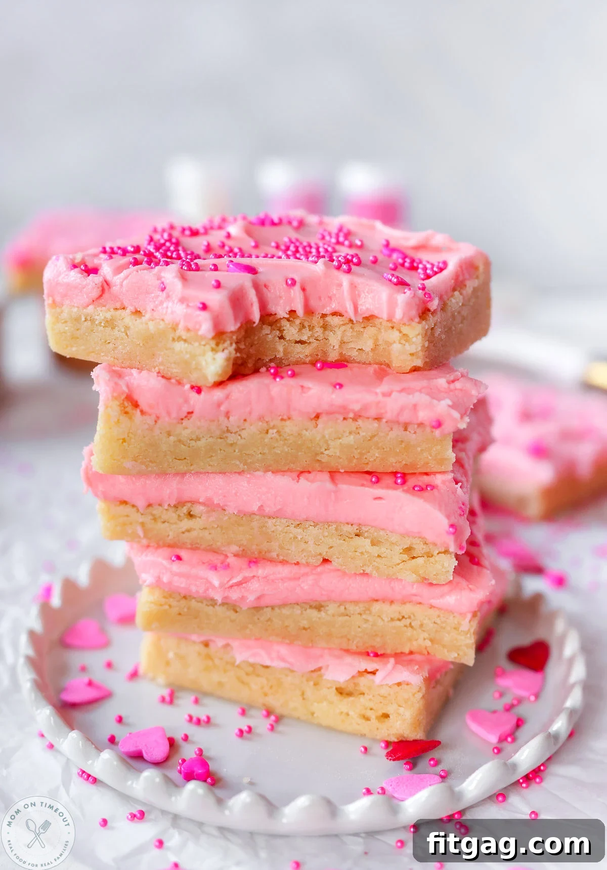 Sweetheart Sugar Cookie Bars 10 A charming stack of four sugar cookie bars, generously frosted with vibrant cherry frosting and adorned with festive sprinkles, promising a delicious treat.