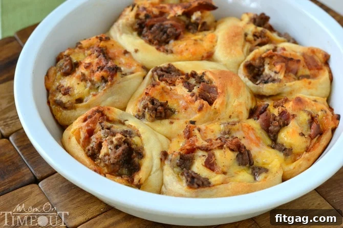 A close-up of a batch of perfectly baked Bacon Cheeseburger Pizza Pinwheels, showcasing the golden crescent roll, melted cheese, and visible bacon bits, served fresh from the oven.