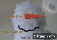 Close-up of a pom-pom snowman's face with carrot nose
