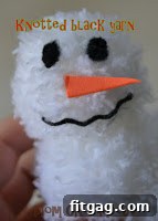 Close-up of a pom-pom snowman's face with yarn eyes
