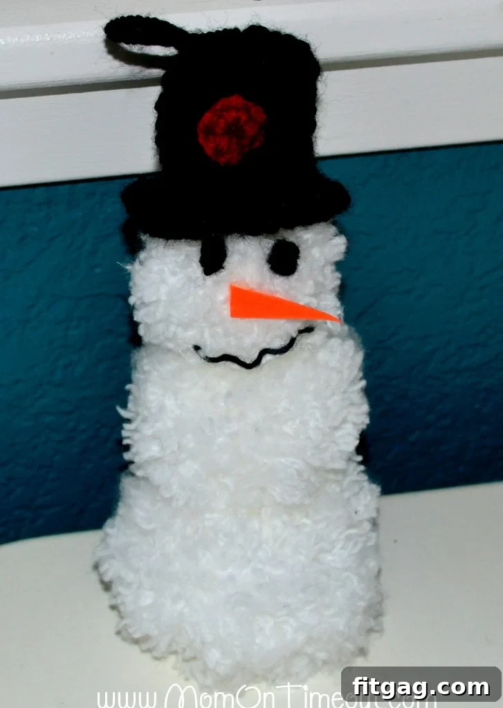 Finished pom pom snowman ornament with hat and scarf, ready for display