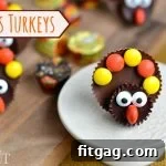 A finished Reese's Turkey, showcasing the detailed candy craft. This festive treat features a full-size Reese's Peanut Butter Cup as the body, a Reese's Dark Miniature for the head, candy eyes, an orange Reese's Piece for the beak, and an array of colorful Reese's Pieces forming the tail feathers. A perfect, edible holiday decoration and dessert.