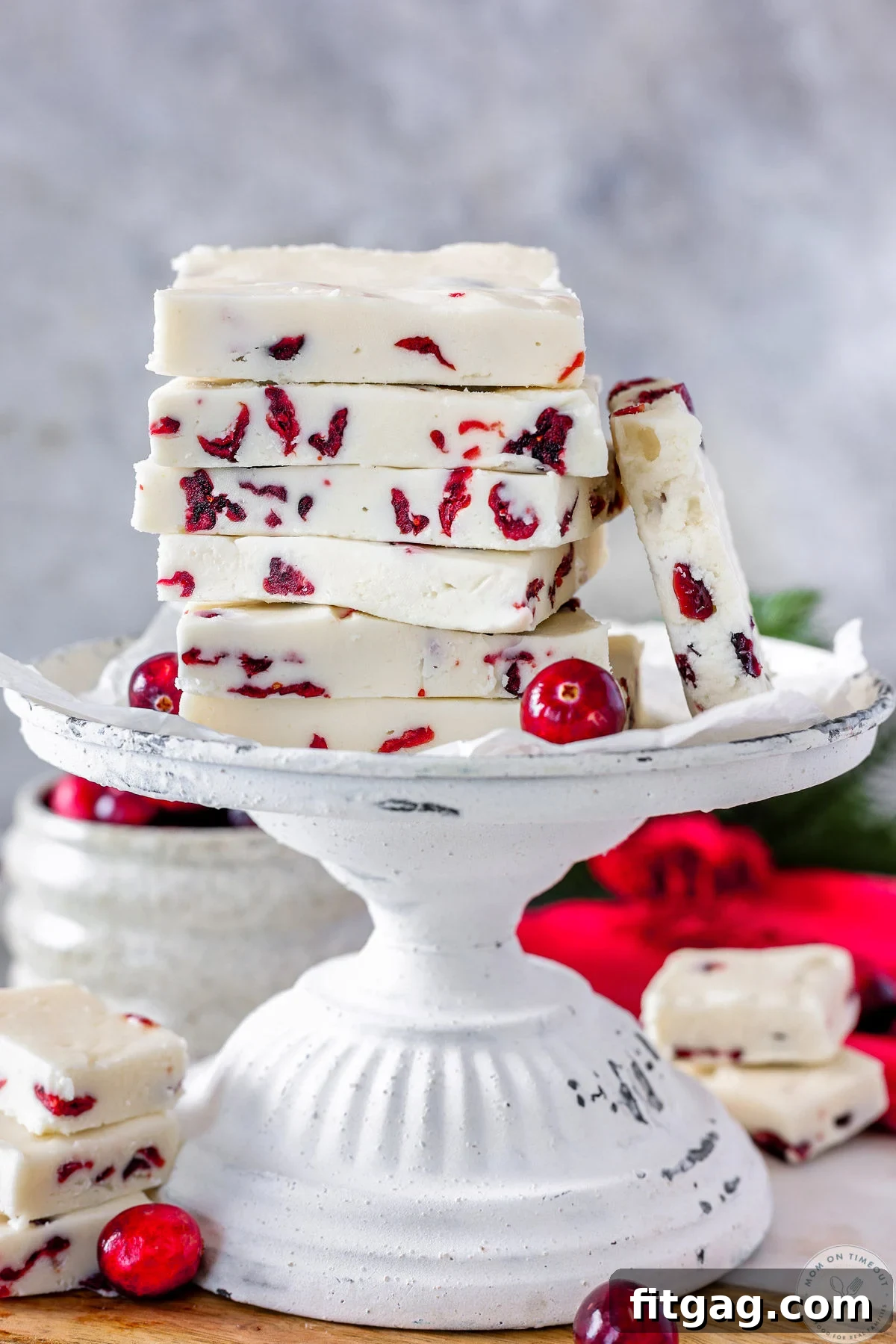 Cranberry fudge cut into rectangles and stacked high on a vintage white stand. 