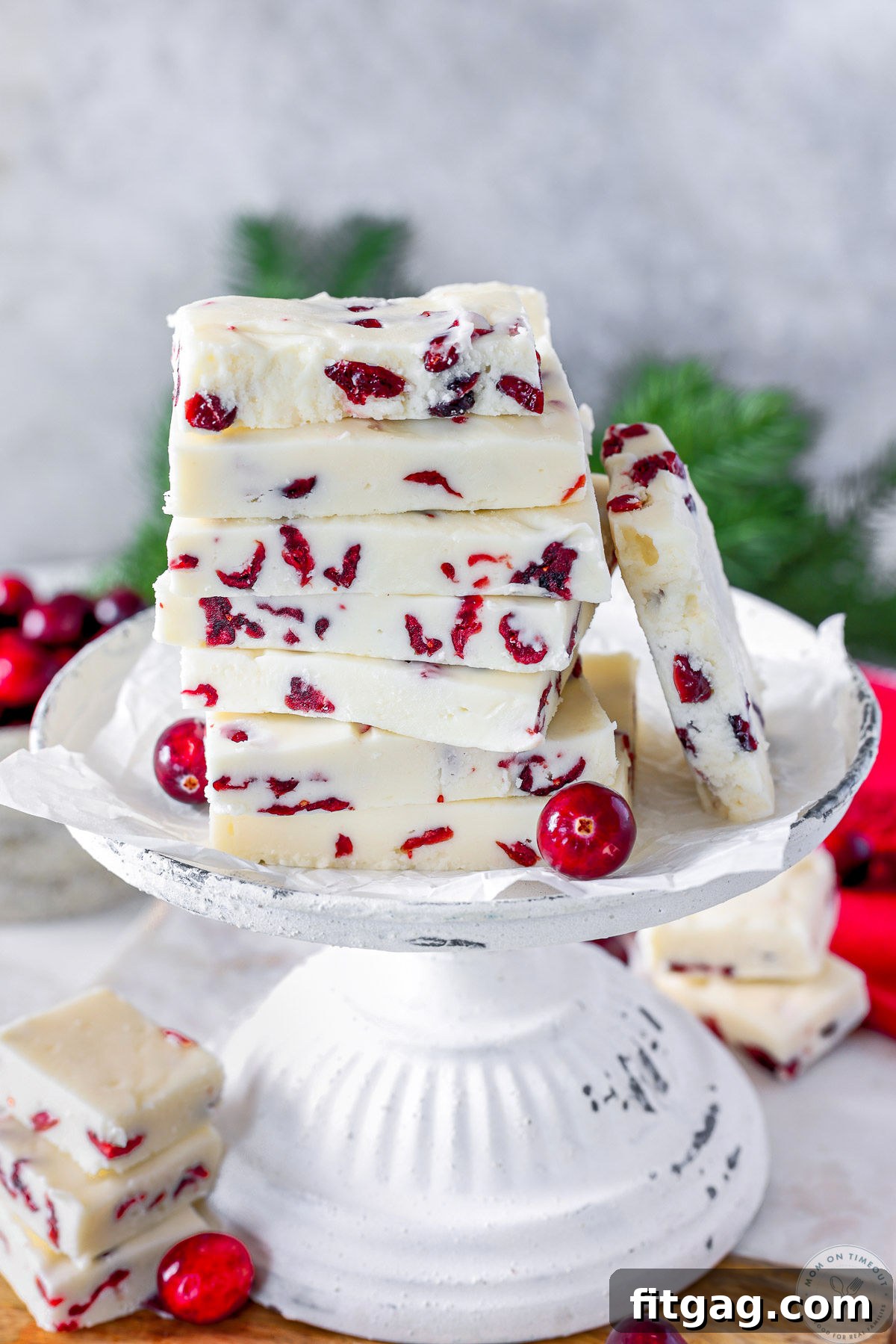 Cranberry fudge cut into rectangles and stacked high on a vintage white stand.