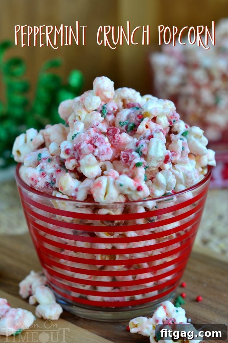 Vibrantly festive Peppermint Crunch Popcorn, coated in white chocolate and adorned with sprinkles, presented in a clear glass jar with a red ribbon for a holiday gift.