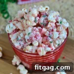 peppermint flavored popcorn in red striped glass bowl made with sprinkles and peppermint candy.