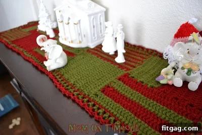 Charming Holiday Crochet Table Runner 7 The completed crocheted Christmas runner beautifully displayed on a mantelpiece, surrounded by holiday decorations