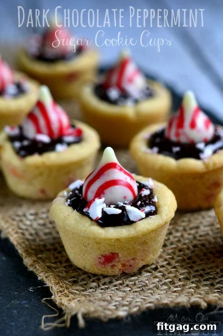 A close-up of a single Dark Chocolate Peppermint Sugar Cookie Cup, highlighting the smooth ganache and vibrant peppermint pieces, inviting a taste.