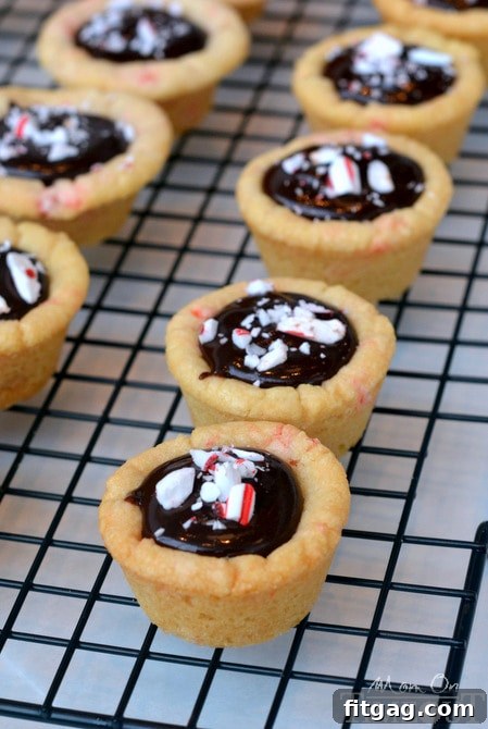 A handful of Dark Chocolate Peppermint Sugar Cookie Cups, showing the delightful combination of dark chocolate ganache and crushed peppermint candy cane topping.