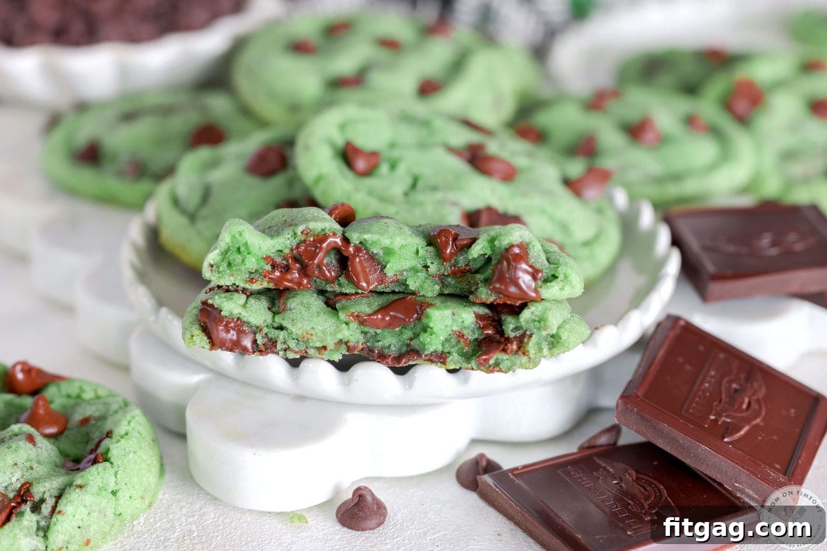 Wide shot of mint chocolate chip cookie cut in half on white plate. 