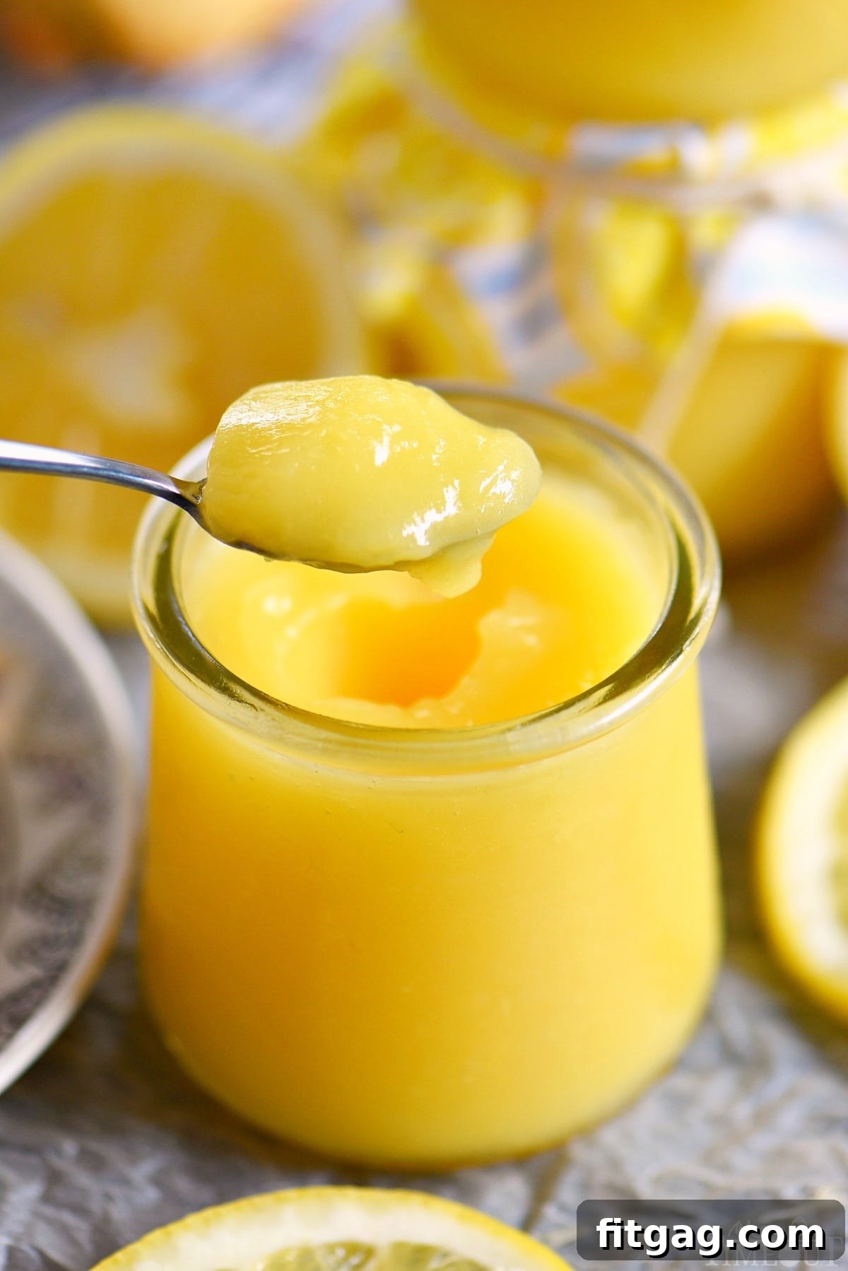 A close-up shot of a spoon scooping luscious lemon curd from a glass jar, highlighting its smooth, thick texture and inviting golden color.