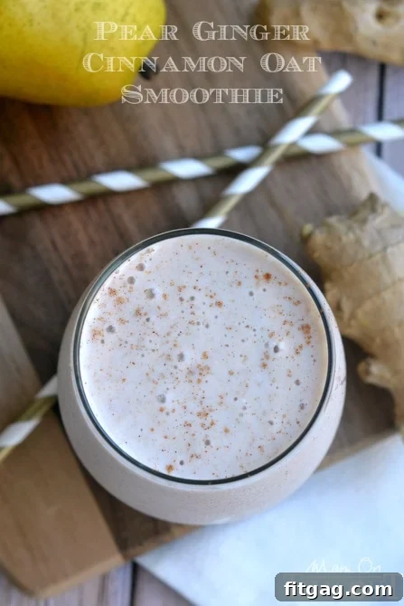 Top-down view of Pear Ginger Cinnamon Oat Smoothie in a short glass with straws, alongside fresh pear and ginger root
