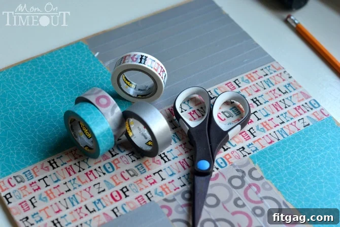 A hand meticulously applying colorful Scotch Expressions Washi Tape to the plywood base of the drawer organizer, following pencil guidelines for precise placement.