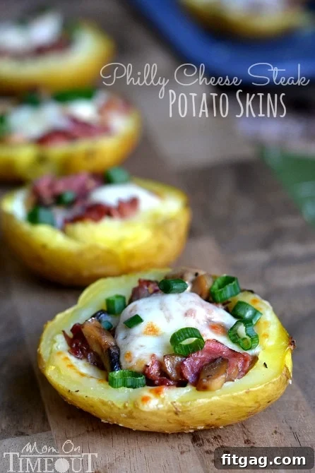 A top-down view of several Philly Cheesesteak Potato Skins, freshly broiled with melted cheese and green onions.