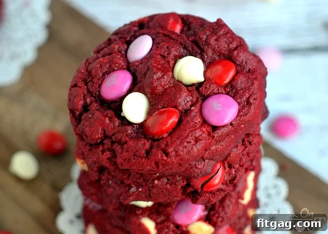 Close-up of freshly baked, soft, and moist Red Velvet White Chocolate Cookies with M&Ms, cooling on a rack.