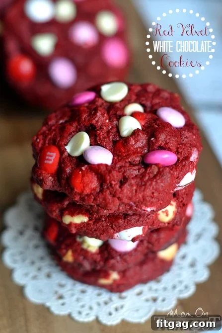 Stack of vibrant Red Velvet White Chocolate Cookies adorned with red, white, and pink M&Ms, ready to be enjoyed.