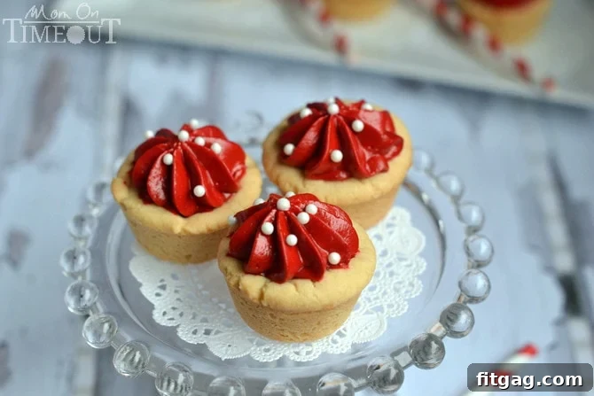 These Red Velvet Cheesecake Cookie Cups are quick, easy, and perfectly festive, featuring sugar cookie cups and a creamy no-bake red velvet cheesecake filling. | MomOnTimeout.com
