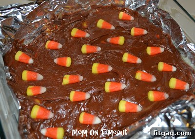 A close-up of a single piece of cut candy corn fudge, showcasing the topping, rich chocolate texture, and perfect squares for serving.