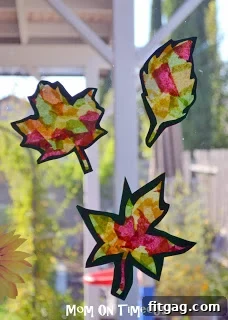 Autumn Leaf Suncatchers 2 Kids hands working on a Stained Glass Fall Leaves craft, showing the process of applying tissue paper to waxed paper.