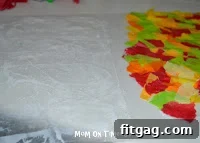 Autumn Leaf Suncatchers 7 Spreading a thin layer of glue on the empty half of a waxed paper sheet, preparing to fold it over.