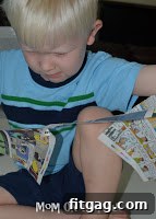 A young boy enthusiastically shredding newspaper with his hands, preparing stuffing for the craft project
