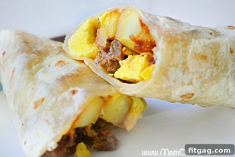 A breakfast burrito cut in half on a white plate, showing the rich filling.