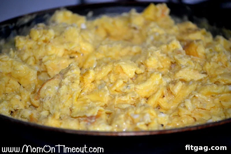 Fluffy scrambled eggs cooking in a nonstick skillet.