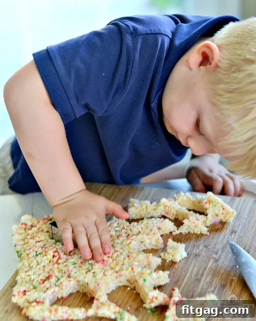 Children's hands cutting Rice Krispies Treats into shapes with cookie cutters