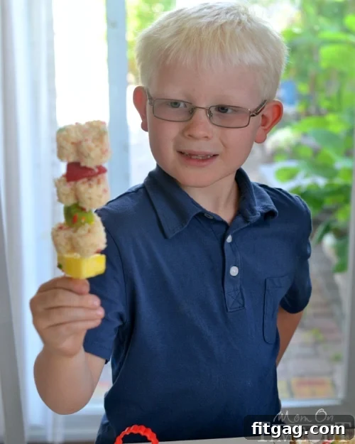 Happy child, Reece, proudly holding and eating a Funfetti Rice Krispies Treats Fruit Kabob