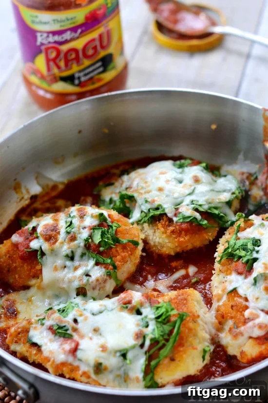 Close-up of golden-brown skillet chicken cutlets topped with rich tomato sauce, fresh spinach, and melted mozzarella cheese, ready to be served.