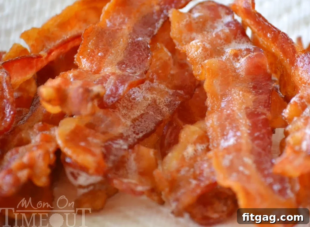 Perfectly baked bacon strips laid out on a baking sheet, showcasing even cooking and crispiness achieved effortlessly in the oven.