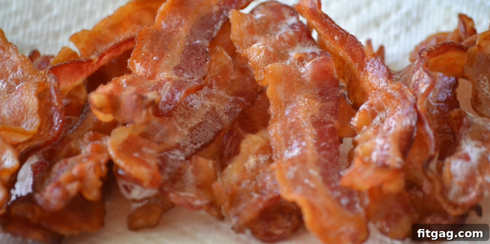 Perfectly crispy bacon strips fresh out of the oven, draining excess grease on paper towels, ready for serving.