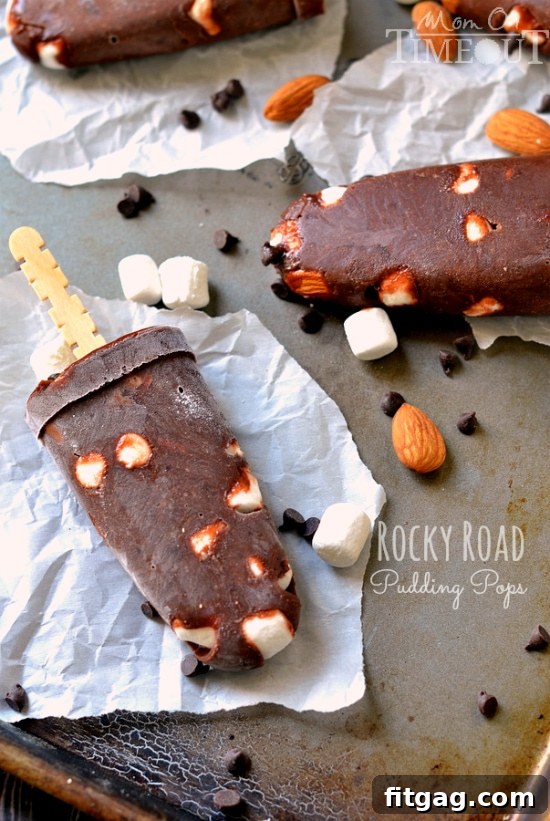 A child's hand holding a refreshing Rocky Road Pudding Pop on a bright, sunny day, capturing the essence of summer fun.