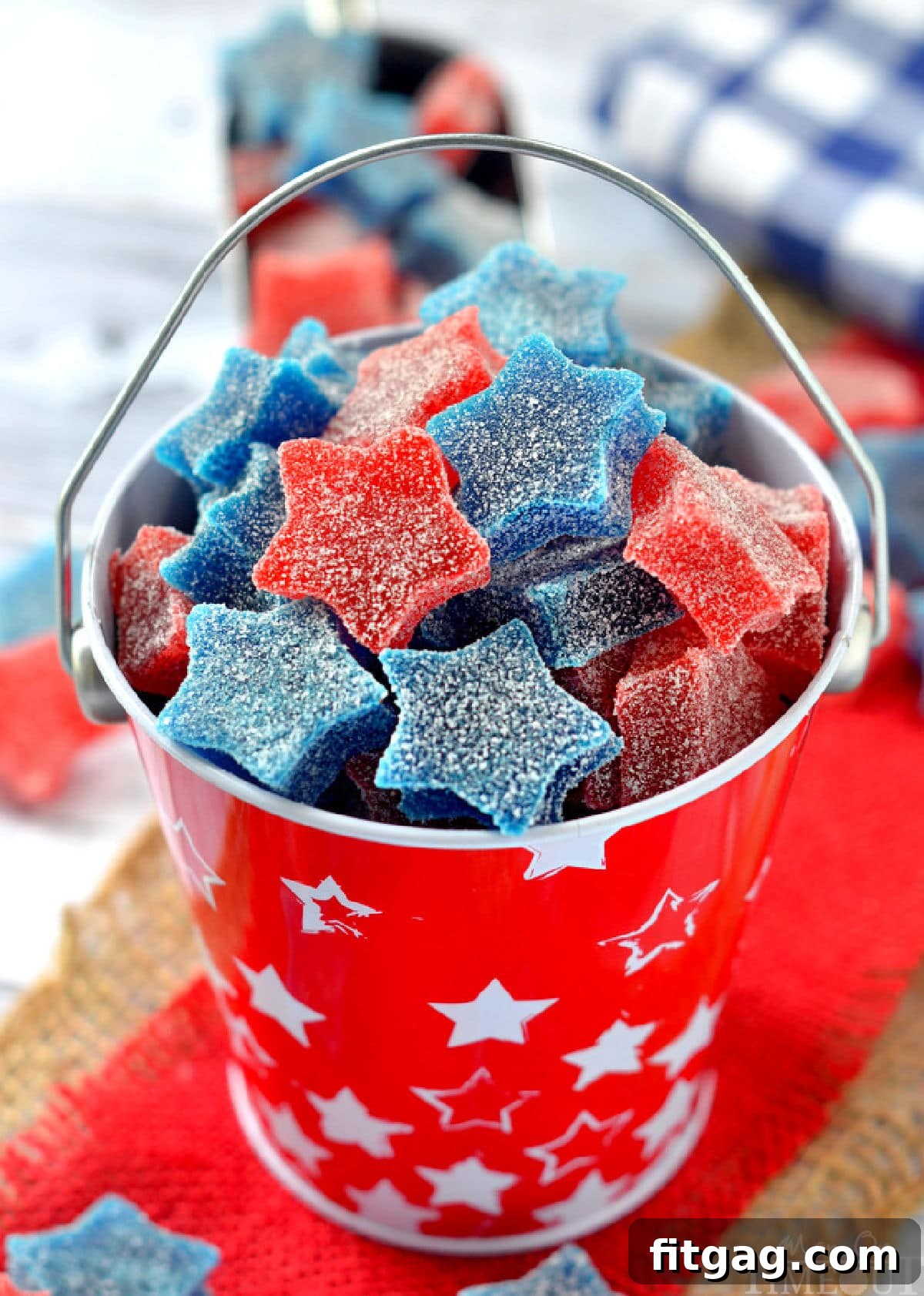 Star shaped gumdrops in red and blue are in a red tin bucket. 