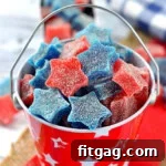 Star shaped gumdrops in red and blue are in a red tin bucket.